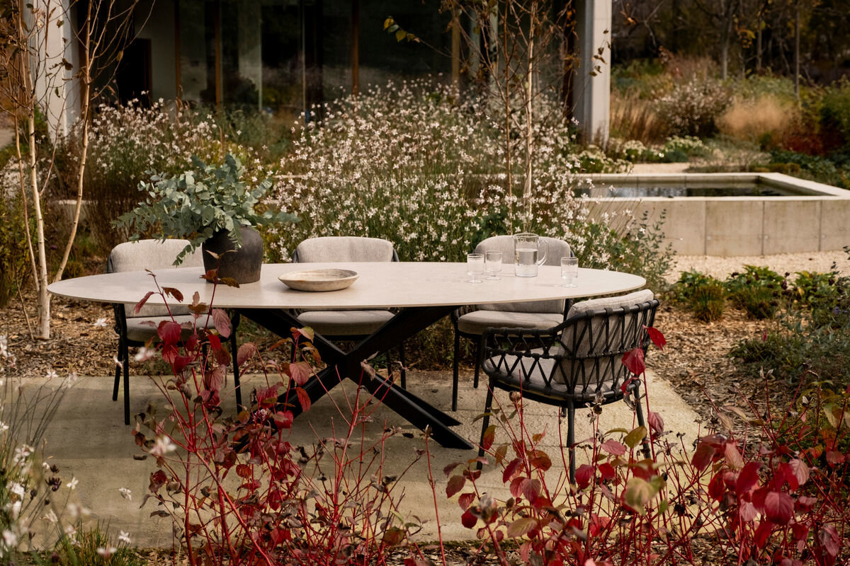 Ovale keramische tuintafel met een x-poot met eetkamerstoelen