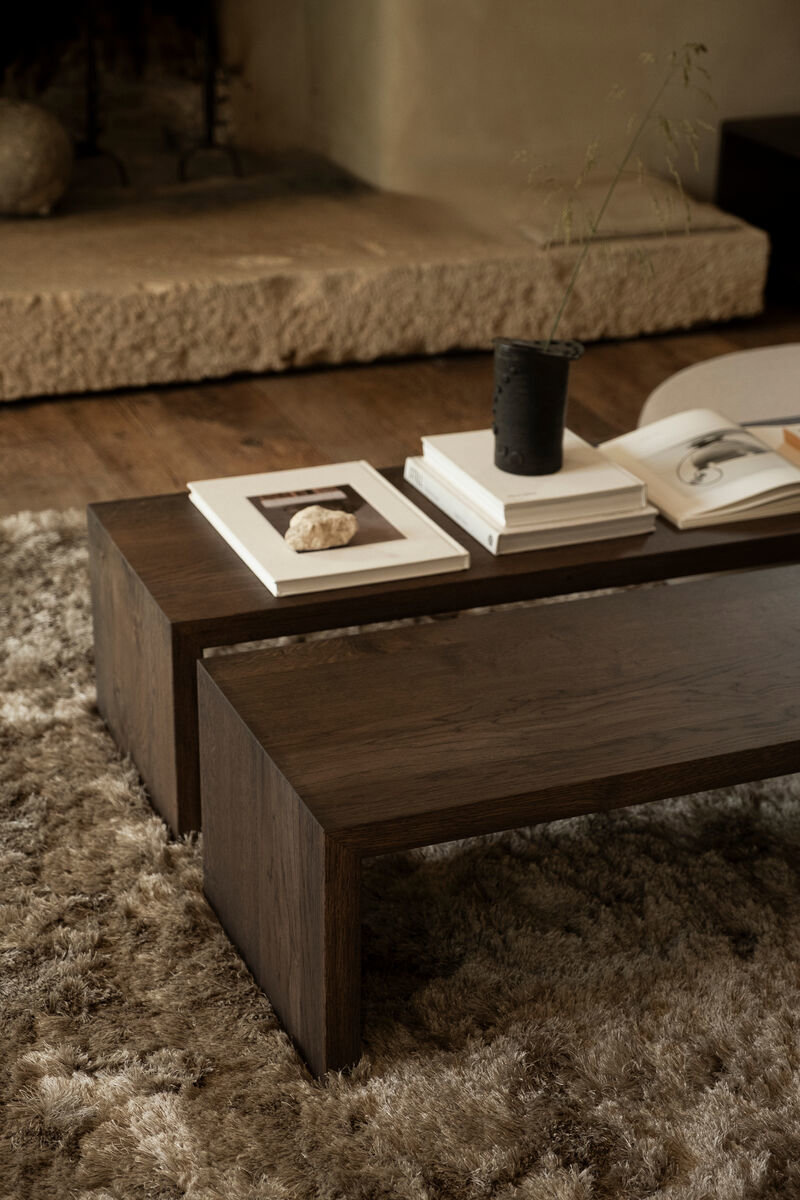 donkere houten salontafel op hoogpolig vloerkleed van table du sud