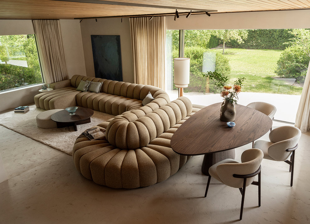 Woonkamer met organische bank en ronde salontafel met poef.