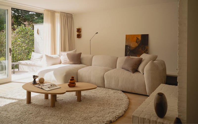 Woontrends 2027 woonkamer met beige loungebank, twee salontafels en rond vloerkleed
